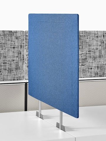 Una pantalla de privacidad azul insertada entre dos superficies de trabajo adyacentes.