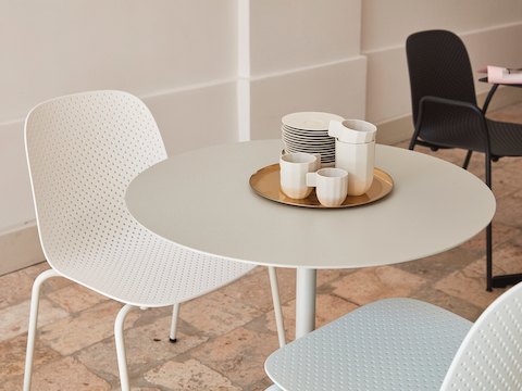 Primer plano de dos sillas 13Eighty en blanco ubicadas junto a una mesa Terrazzo en blanco.