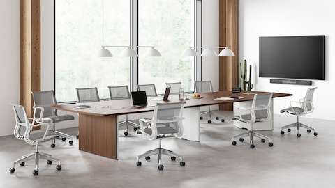 Un esquema de oficina con una mesa de conferencias Headway con una base de gabinete rodeada por sillas para oficinas Setu en gris y blanco.