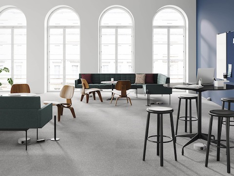 Una oficina abierta con sofás Tuxedo, sillas de madera laminada moldeada Eames con mesas Eames, todo con conexión a energía y datos mediante rieles por debajo de la alfombra Logic Reach y micro torres Logic.
