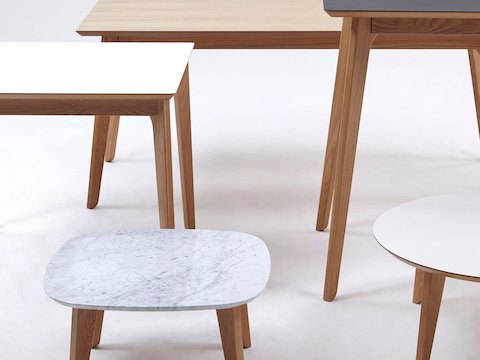 Una mesa de café Dalby de NaughtOne cuadrada con superficie de mármol blanco, dispuesta con otras mesas de la familia Dalby de diversas alturas y acabados.