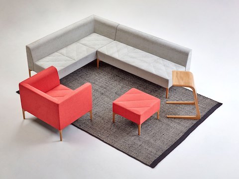 Banco e Hatch Lounge Chair vermelha em uma configuração de assento com sofá modular Hatch cinza, mesa de centro Trace e mesa Riley.