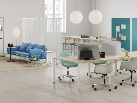 Espacio de oficina de planta abierta con sillas de trabajo, mesas de proyectos, mesas de altura ajustable, sillas acolchonadas y paredes móviles.