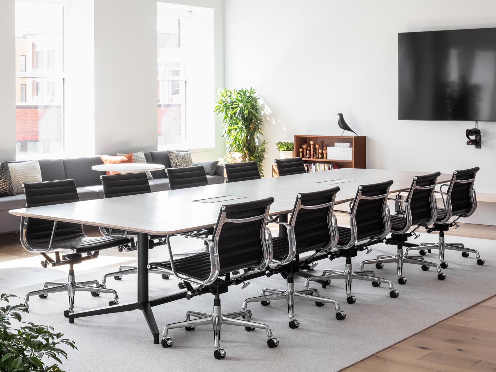 Una gran sala de conferencias bien iluminada con una mesa Headway y diez sillas negras Eames Aluminum Group.