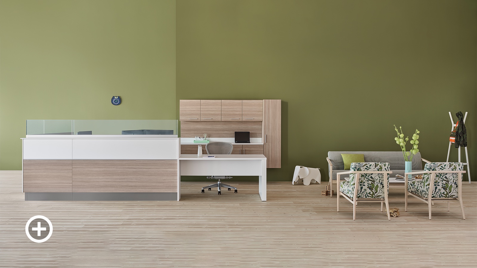 A prefab Commend Nurses Station with glass screens serving as a reception desk in an outpatient space including Palisade chairs, sofa, and table.