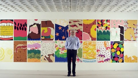 El diseñador gráfico Steve Frykholm se encuentra ante una pared de carteles. Seleccione para ir a la entrevista de la WHY Magazine de Frykholm.
